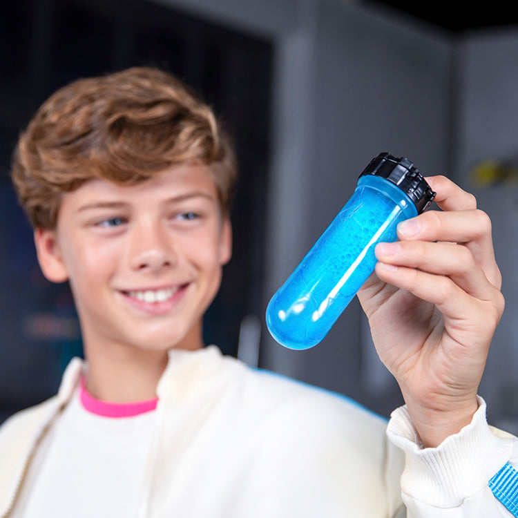 Young boy holding a blue test tube filled with fizzing liquid, showcasing MrBeast Lab Swarms Lab experience.