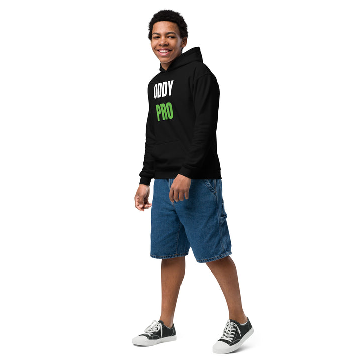 A smiling boy wearing an Oddy Pro Youth heavy blend hoodie, paired with denim shorts and casual sneakers.